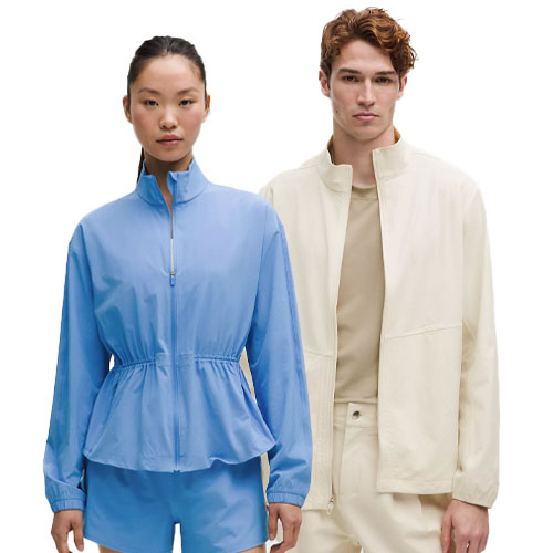 A woman wears a light blue zip-up jacket with matching shorts, and a man wears a light beige jacket over a beige shirt and pants.
