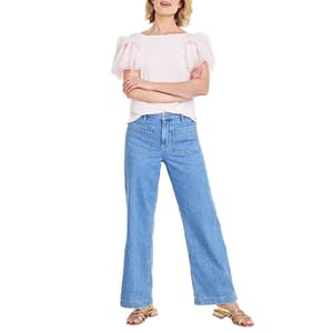 Women's wide-leg jeans in light blue denim featuring front patch pockets, paired with a short-sleeve white top with pink puffed sleeves.