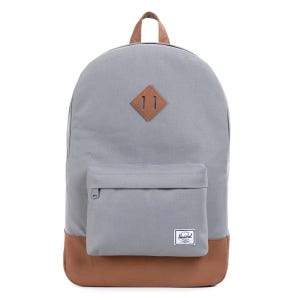 A gray backpack with brown accents, featuring a front pocket, a leather loop, and a patch label, commonly used for casual or school purposes.