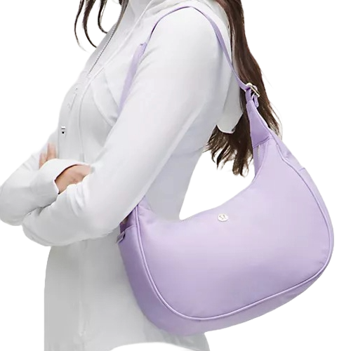 A person is carrying a lavender shoulder bag with a curved shape, paired with a white button-up shirt.