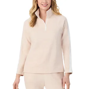 A woman is wearing a light beige quarter-zip pullover with long sleeves and a high collar. The sleeves have a white stripe detail.