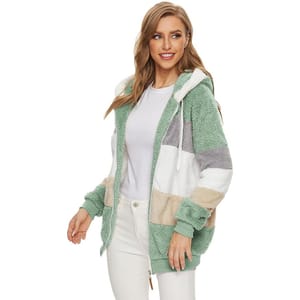 A cozy Sherpa jacket featuring a colorblock pattern in shades of green, white, gray, and beige. The jacket has a hood and elastic cuffs, paired with a simple white t-shirt and white pants.