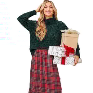 A person in a green knitted sweater and red plaid skirt holds wrapped gifts, one with a red ribbon.