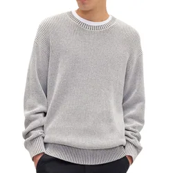 A person is wearing a light gray knit sweater with a ribbed design, layered over a white shirt, and paired with dark pants.