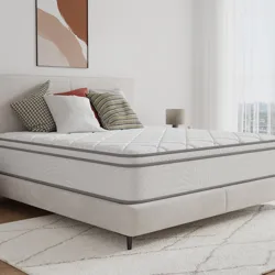 A 14-inch hybrid queen mattress with a quilted top, featuring a white and gray design. It rests on a light upholstered bed frame with a neutral-toned, modern bedroom setting, including decorative pillows and a patterned area rug.