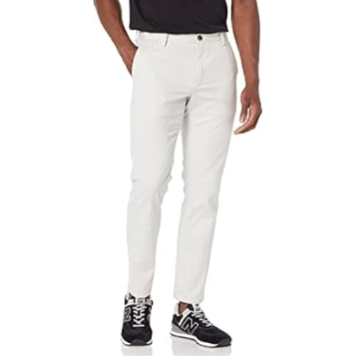 A person is wearing slim-fit white pants paired with black sneakers and a black top.
