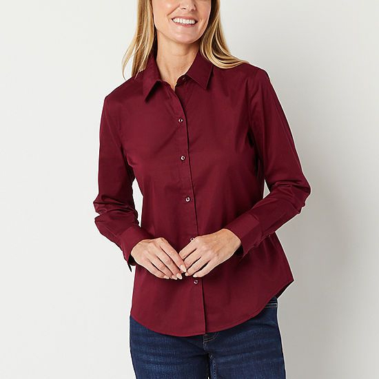 A woman wearing a burgundy button-up blouse with long sleeves and a collar, paired with blue denim jeans.