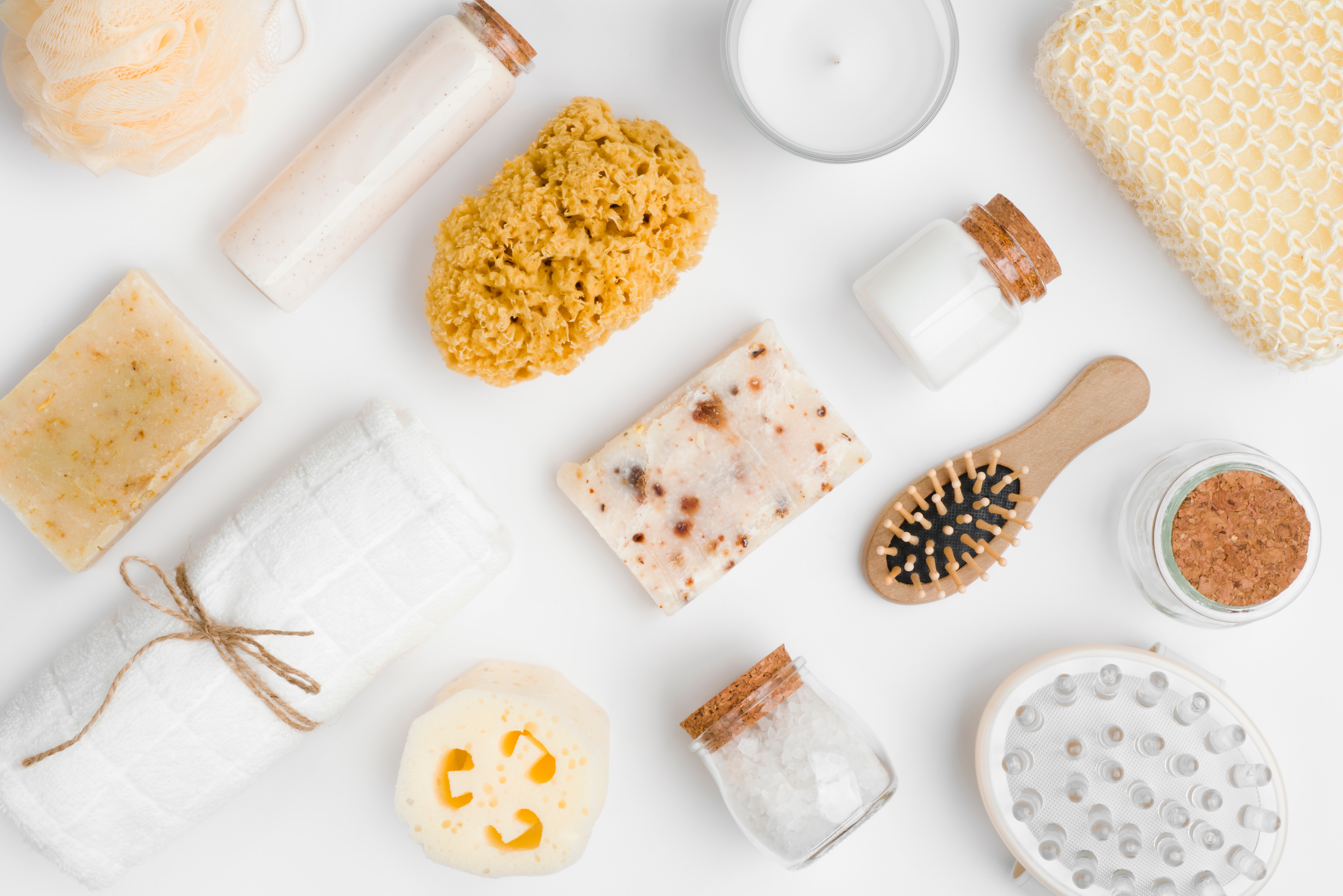 Assorted bath and body care items including soaps, loofah, sea sponges, a hairbrush, bath salts, a candle, and a massage tool.