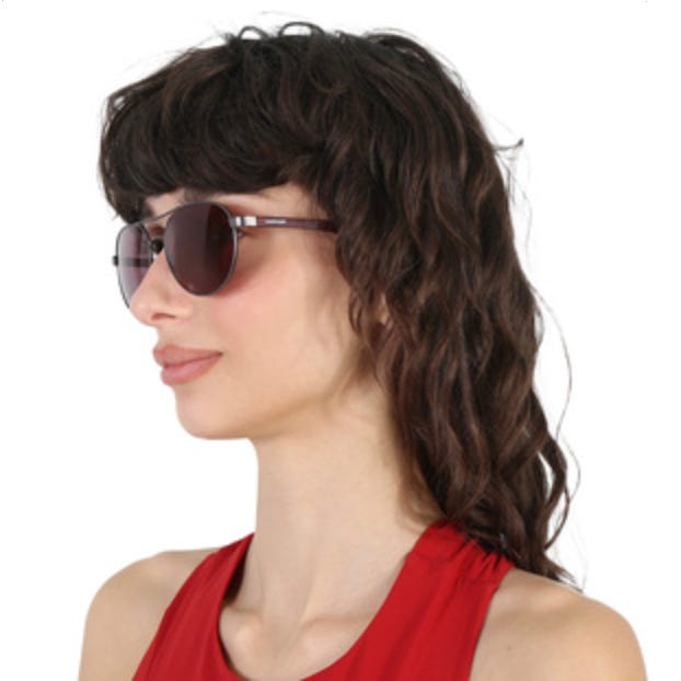 Calvin Klein sunglasses with round, dark lenses and sleek brown frames. The design is contemporary and minimalist, paired with a red top.