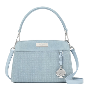 A light blue Kate Spade New York handbag featuring a top handle and detachable shoulder strap, with a spade-shaped charm and a textured fabric design.