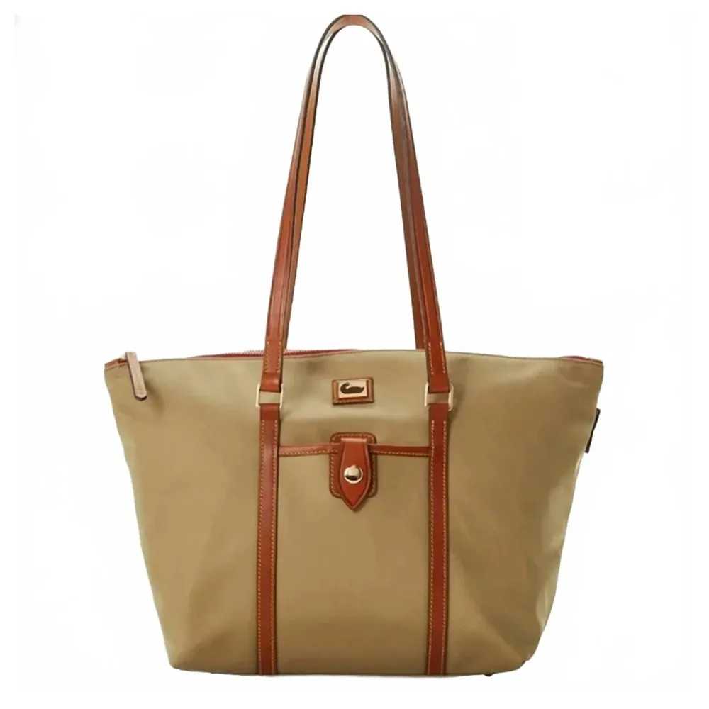 A tan tote bag with brown leather straps and trim, featuring a front pocket with a gold clasp.