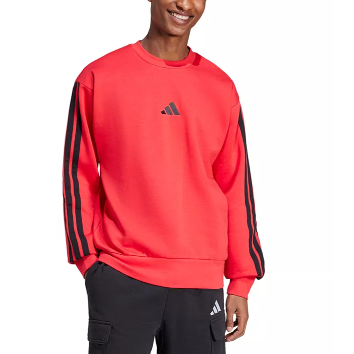 A person is wearing a red Adidas sweatshirt with black stripes on the sleeves and a small logo on the chest. They are also wearing black pants with the Adidas logo.