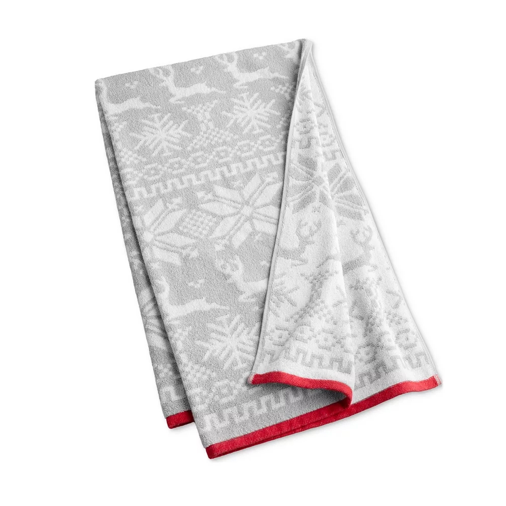 A gray and white blanket features a festive design with snowflakes and reindeer, accented by a red trim along the edges.