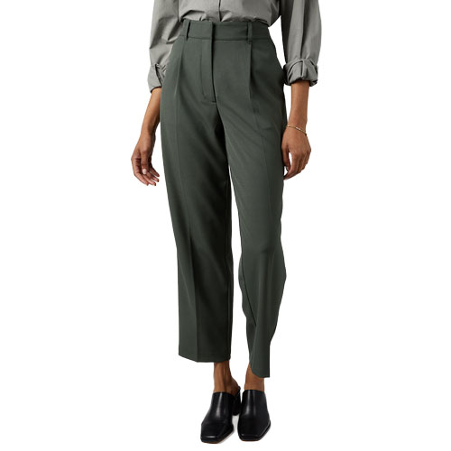 A person wearing high-waisted, dark green tailored pants with a pleated front, paired with a long-sleeved, cuffed shirt and black slip-on shoes.