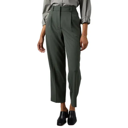 A person wearing high-waisted, dark green tailored pants with a pleated front, paired with a long-sleeved, cuffed shirt and black slip-on shoes.