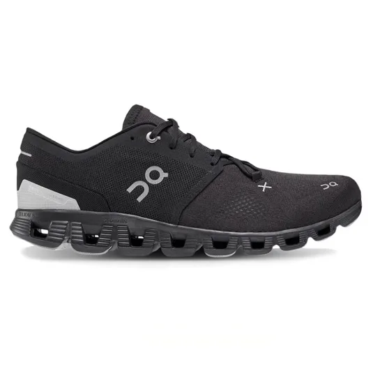 A black athletic shoe with distinctive cushioning and perforated sole design, featuring the On logo.
