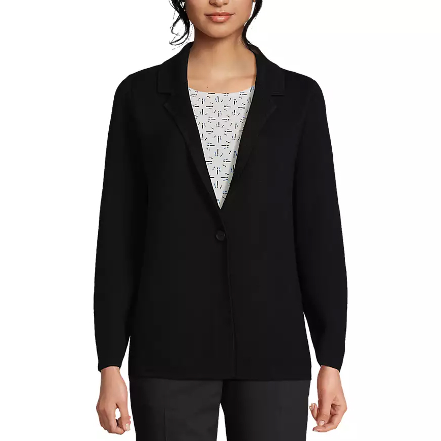 A woman is wearing a black blazer over a patterned top, paired with dark pants.