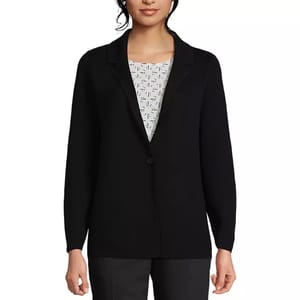 A woman is wearing a black blazer over a patterned top, paired with dark pants.