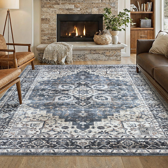 A traditional-patterned, 8' x 10' machine-washable rug features a central medallion design in shades of blue, gray, and ivory, placed in a cozy living room with leather seating, a fireplace, and wooden accents.