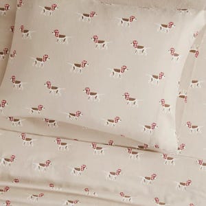 Cream-colored bedding with a repeated pattern of small dogs wearing red bandanas.