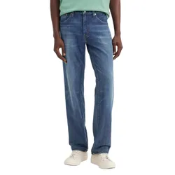 A person is wearing straight-leg blue jeans paired with a light green shirt and white sneakers.