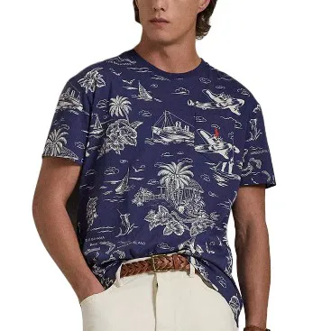 A man is wearing a navy blue T-shirt with a white tropical print, featuring palm trees, boats, and animals, paired with light-colored pants and a braided brown belt.