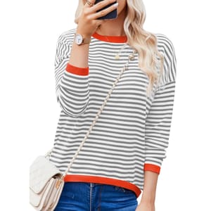 Woman in a striped long-sleeve shirt with red trim, wearing jeans, a quilted white handbag with a chain strap, a wristwatch, and layered necklaces.