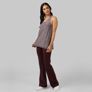 A woman is wearing a gray sleeveless top and maroon flared pants.