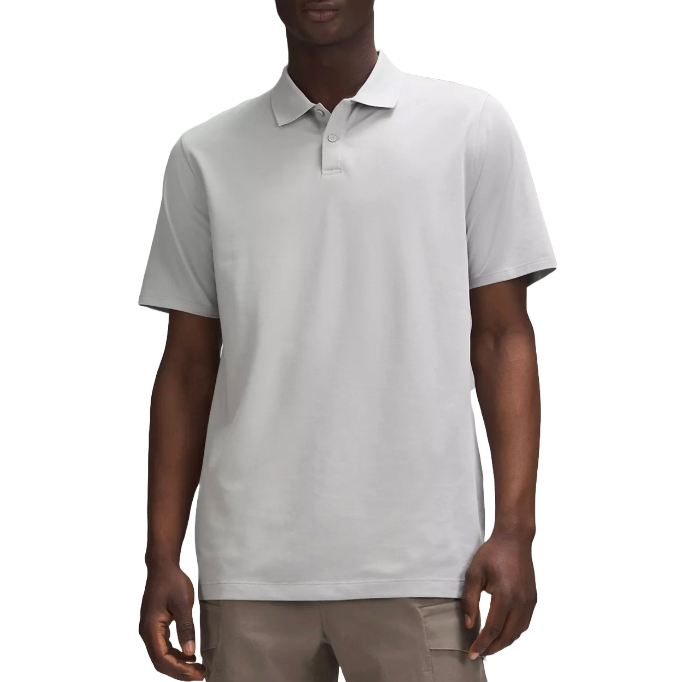 A man is wearing a light gray short-sleeve polo shirt paired with light brown pants.