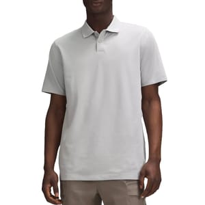 A man is wearing a light gray short-sleeve polo shirt paired with light brown pants.