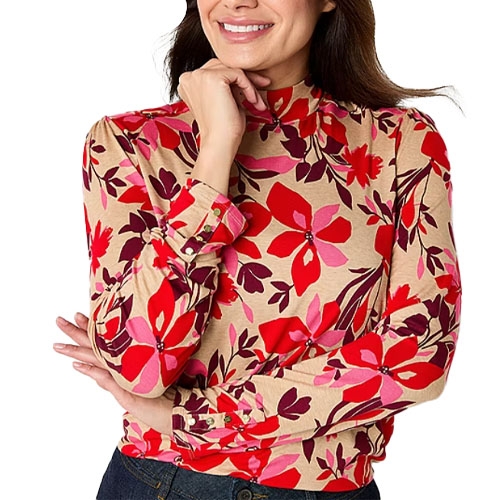 A woman is wearing a long-sleeve top with a vibrant floral pattern in red, pink, and purple on a beige background.
