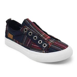 Casual slip-on sneaker with a plaid fabric design, featuring silver eyelets and a white rubber sole.