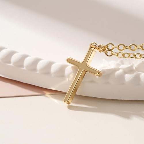 A gold cross pendant necklace rests on a white surface, featuring a simple and elegant design with a delicate gold chain.