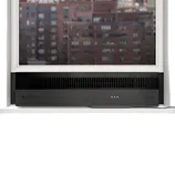 A window air conditioner is installed below a partially open window overlooking a cityscape. The unit features a sleek black design with a visible power cord.