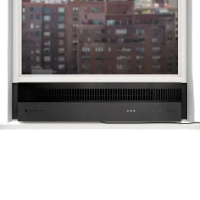 A window air conditioner is installed below a partially open window overlooking a cityscape. The unit features a sleek black design with a visible power cord.