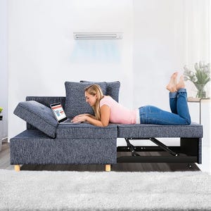 A woman is relaxing on a blue sectional sofa with an adjustable headrest and a built-in storage compartment.