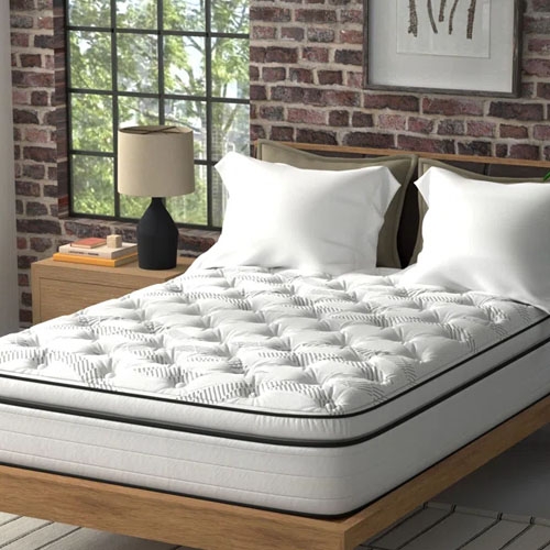 a white mattress with two white pillows in front of a red brick wall