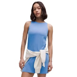 A sleeveless, light blue, organic cotton dress with a high neckline, featuring a white sweater tied around the waist.