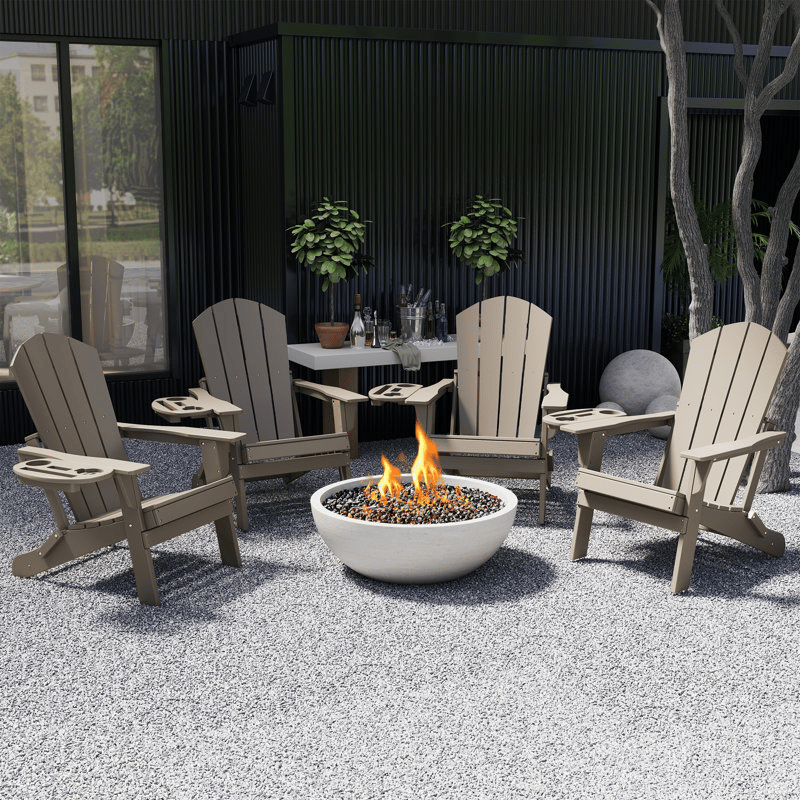 A patio setup featuring four beige Adirondack chairs encircling a fire pit. There is a table with plants and bottled drinks in the background, set against a dark wall.