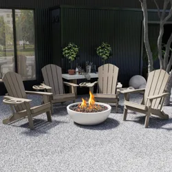 A patio setup featuring four beige Adirondack chairs encircling a fire pit. There is a table with plants and bottled drinks in the background, set against a dark wall.