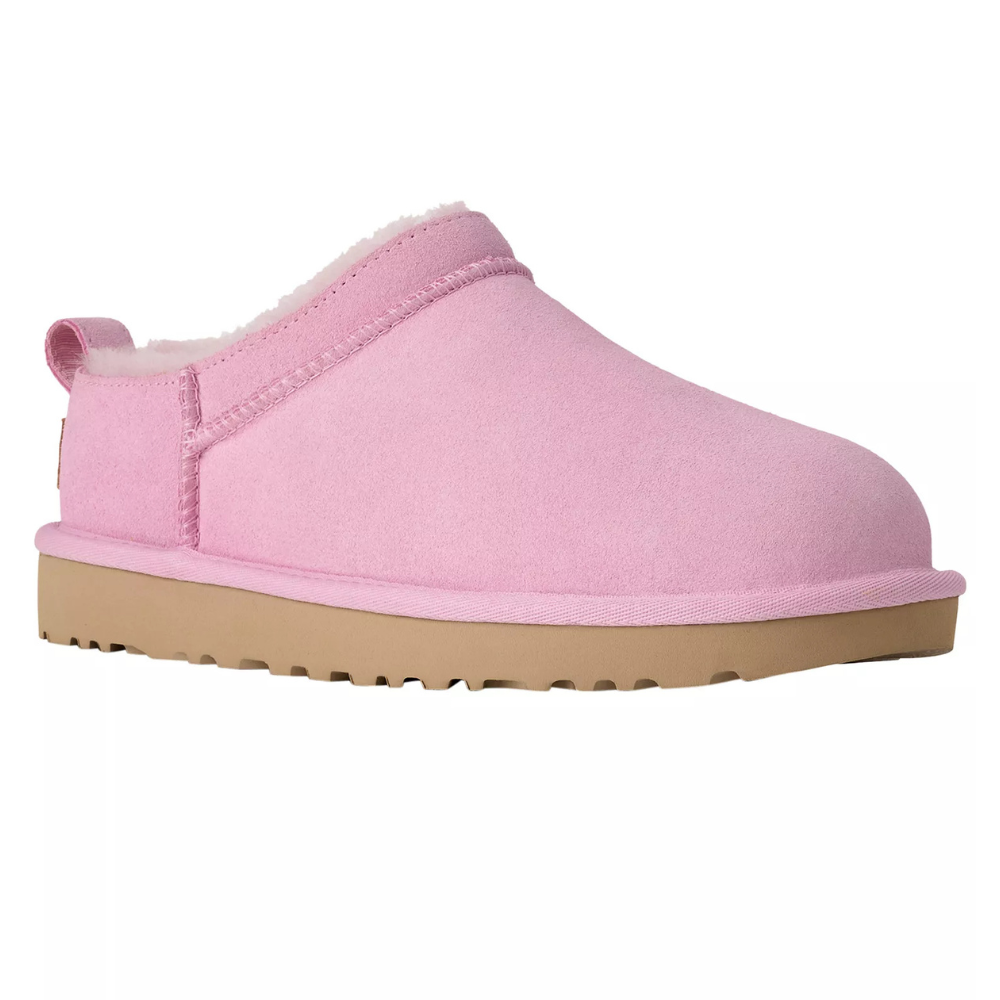 A pink slip-on slipper with a shearling lining and tan rubber sole, featuring a pull tab at the heel.
