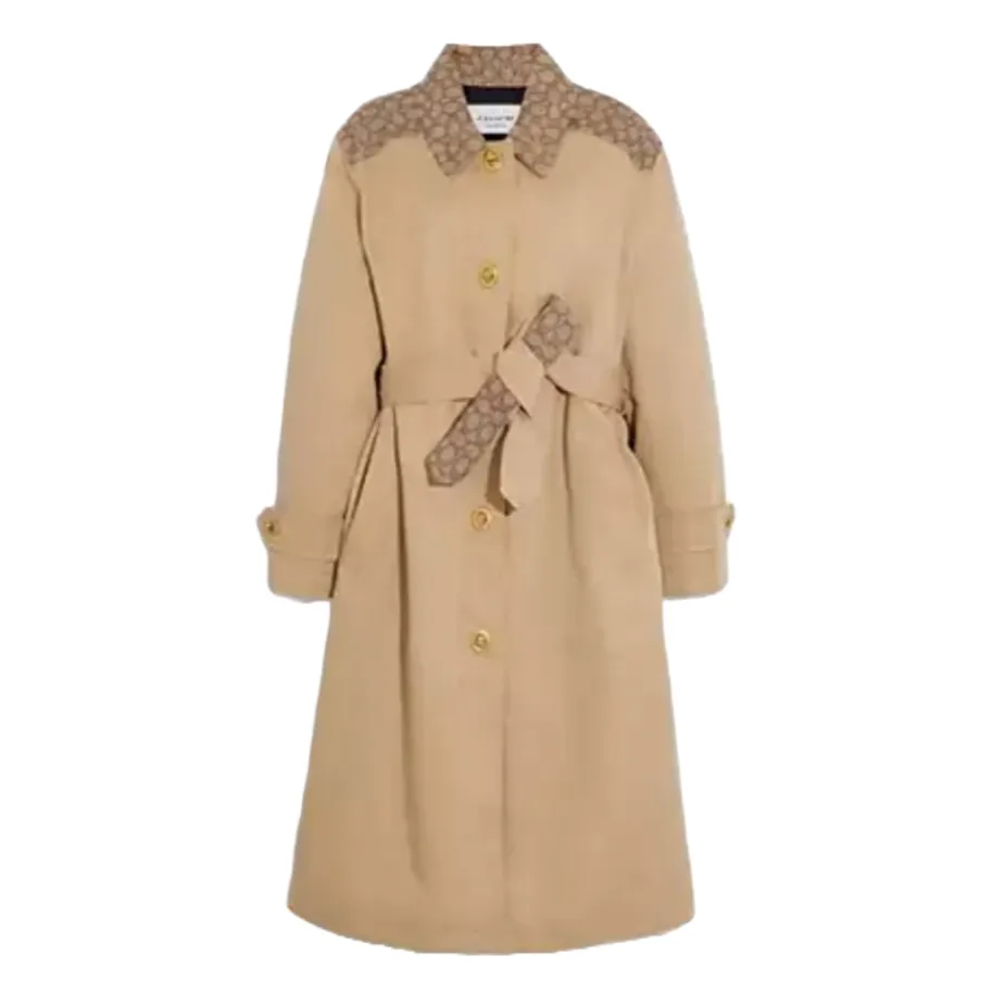 Beige long trench coat with button closure, featuring monogram accents on the shoulders and a matching monogram belt.