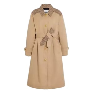 Beige long trench coat with button closure, featuring monogram accents on the shoulders and a matching monogram belt.