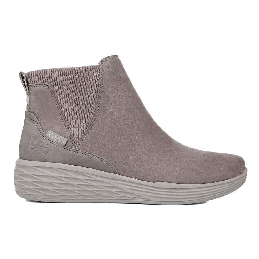 A gray, ankle-high boot with a ribbed elastic side panel and textured sole, featuring \“Ryka\“ branding on the heel.