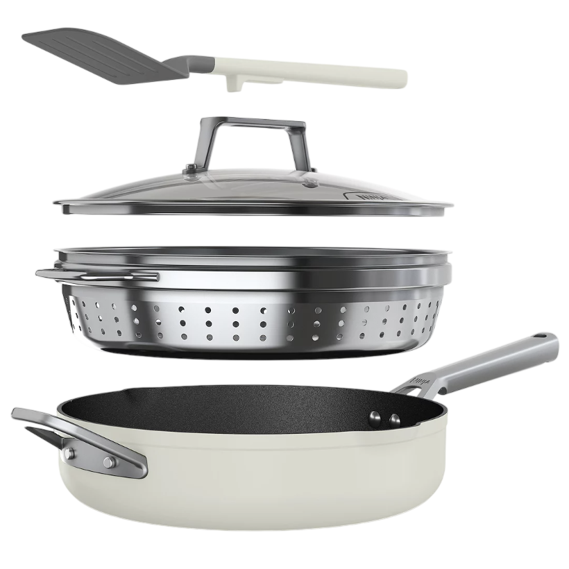 Cookware set including a skillet, a stainless-steel steamer insert, a glass lid, and a spatula.