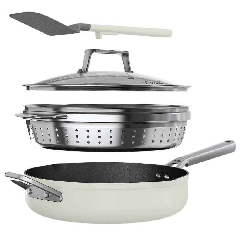 Cookware set including a skillet, a stainless-steel steamer insert, a glass lid, and a spatula.
