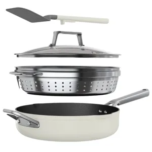 Cookware set including a skillet, a stainless-steel steamer insert, a glass lid, and a spatula.