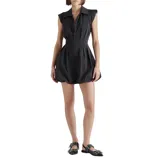 A woman wears a black sleeveless, collared dress with a zip front and a bubble hem, paired with black flats featuring metal buckle details.