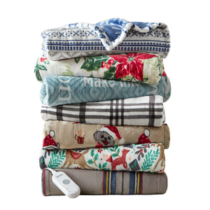 A stack of patterned fleece blankets with various designs, including festive and plaid patterns, topped with a remote control for an electric blanket.