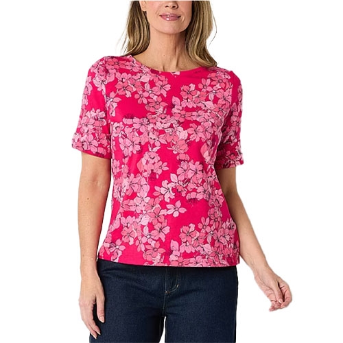 A woman wearing a pink floral-patterned short-sleeve shirt paired with dark jeans.